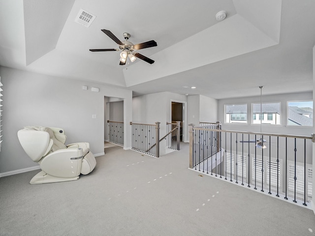 sitting room with baseboards, visible vents, a raised ceiling, carpet flooring, and an upstairs landing