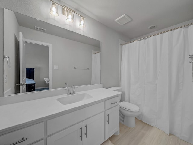 bathroom featuring visible vents, vanity, toilet, and wood finished floors