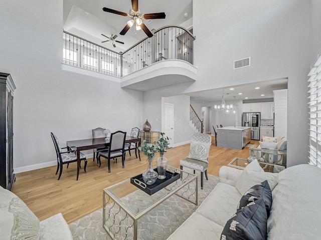 living area featuring stairway, visible vents, light wood-style flooring, and baseboards