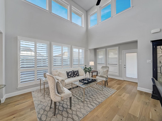 living room with a high ceiling, wood-type flooring, and baseboards