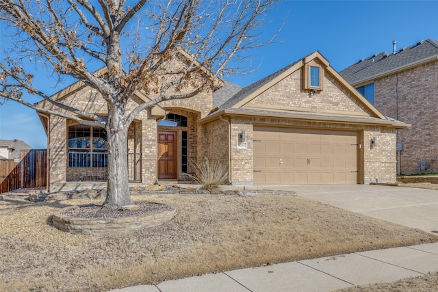 traditional-style home featuring brick siding, a shingled roof, concrete driveway, an attached garage, and fence