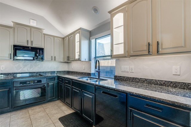 kitchen featuring light tile patterned floors, dark stone counters, vaulted ceiling, black appliances, and a sink