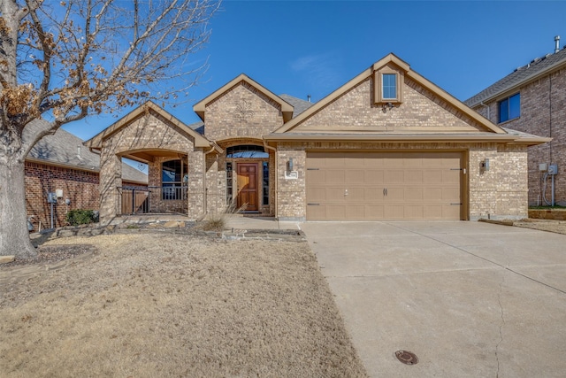 french country style house featuring an attached garage, concrete driveway, and brick siding