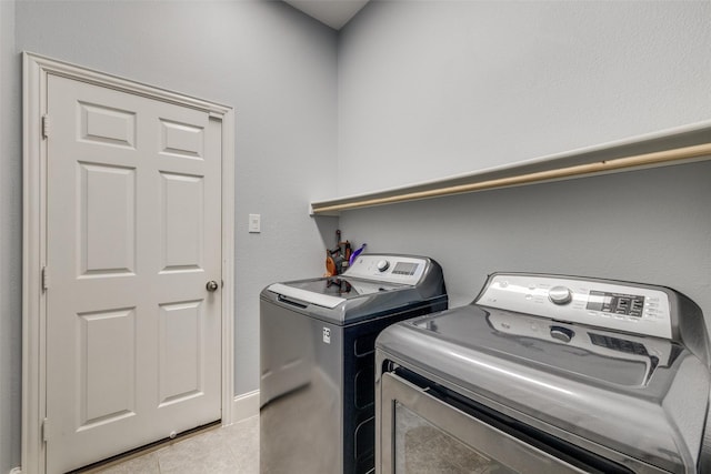 clothes washing area featuring washer and dryer, laundry area, and light tile patterned floors