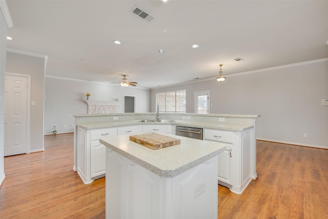 kitchen with light wood finished floors, visible vents, white cabinets, a large island, and a sink