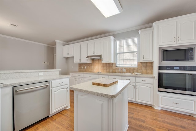 3409 Windridge Dr, Garland, TX 75043 - kitchen featuring stainless steel appliances, under cabinet range hood, ornamental molding, light wood-style floors, and white cabinetry