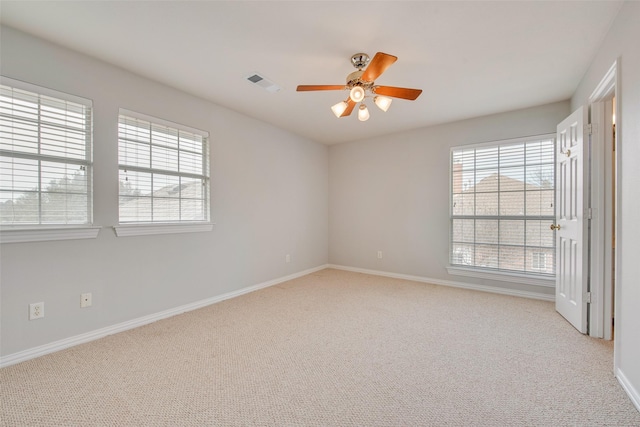 unfurnished room with baseboards, visible vents, a ceiling fan, and light colored carpet