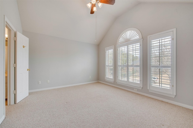 carpeted spare room with a ceiling fan, lofted ceiling, plenty of natural light, and baseboards