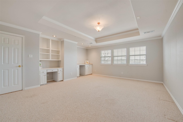 interior space featuring baseboards, a raised ceiling, and built in desk