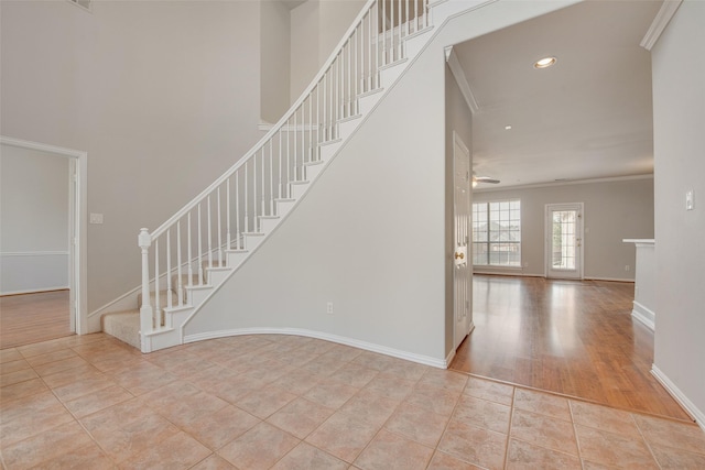 entrance foyer with ornamental molding, a ceiling fan, tile patterned flooring, baseboards, and stairs