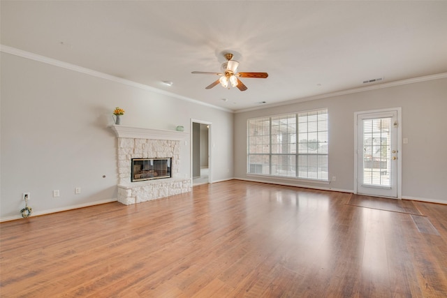 unfurnished living room featuring crown molding, visible vents, wood finished floors, and a stone fireplace