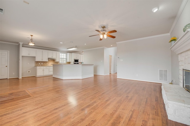 unfurnished living room with a ceiling fan, visible vents, a fireplace, and light wood-style flooring