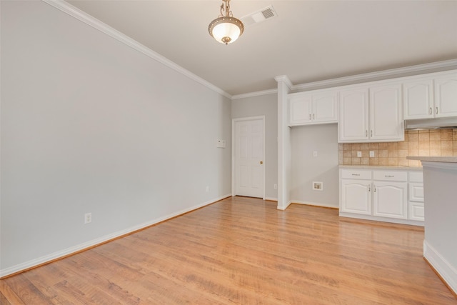 3409 Windridge Dr, Garland, TX 75043 - kitchen featuring under cabinet range hood, ornamental molding, light wood-style floors, white cabinetry, and baseboards
