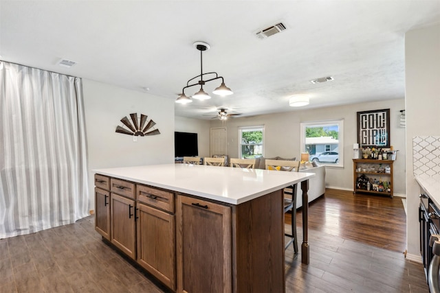 kitchen with light countertops, dark wood finished floors, visible vents, and a kitchen breakfast bar