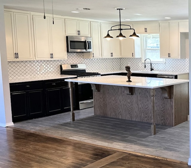 kitchen with stainless steel appliances, dark wood finished floors, light countertops, and a center island