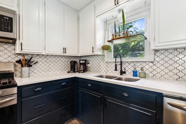 kitchen featuring tasteful backsplash, appliances with stainless steel finishes, light countertops, white cabinetry, and a sink