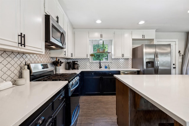 kitchen with white cabinets, stainless steel appliances, a sink, and light countertops