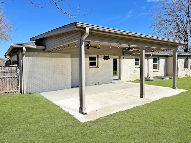 back of property featuring ceiling fan, a patio, brick siding, fence, and a lawn