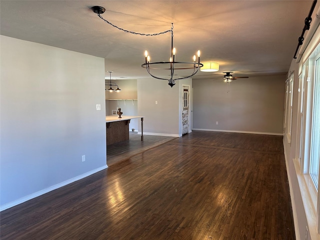 unfurnished living room featuring dark wood-style floors, baseboards, and ceiling fan with notable chandelier