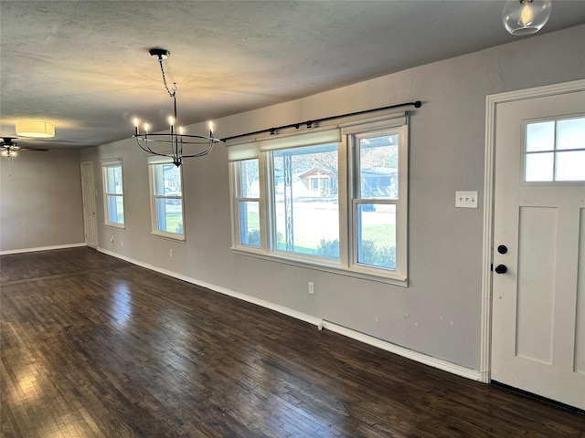 interior space with ceiling fan with notable chandelier, a textured ceiling, baseboards, and wood finished floors