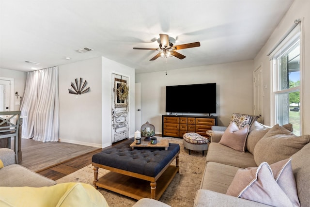 living room with a ceiling fan, visible vents, baseboards, and wood finished floors