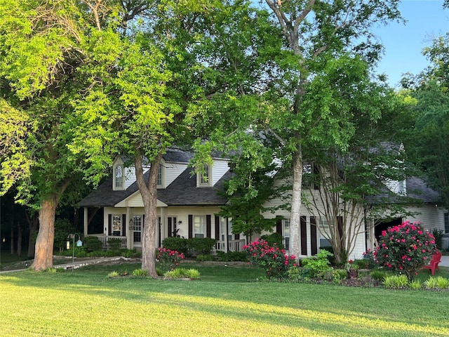 cape cod house featuring roof with shingles and a front lawn