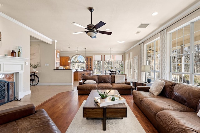 living area featuring light wood finished floors, visible vents, ceiling fan, and ornamental molding