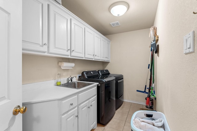 clothes washing area featuring washer and clothes dryer, a sink, light tile patterned floors, visible vents, and cabinet space