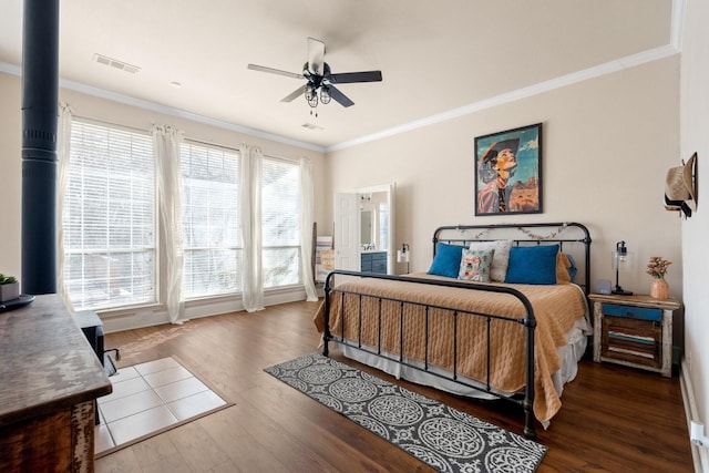 bedroom featuring wood finished floors, ornamental molding, ceiling fan, and visible vents