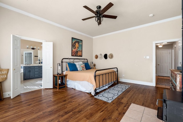 bedroom with baseboards, connected bathroom, wood finished floors, and crown molding