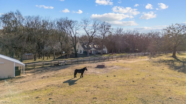 view of yard featuring an outbuilding, fence, and a rural view