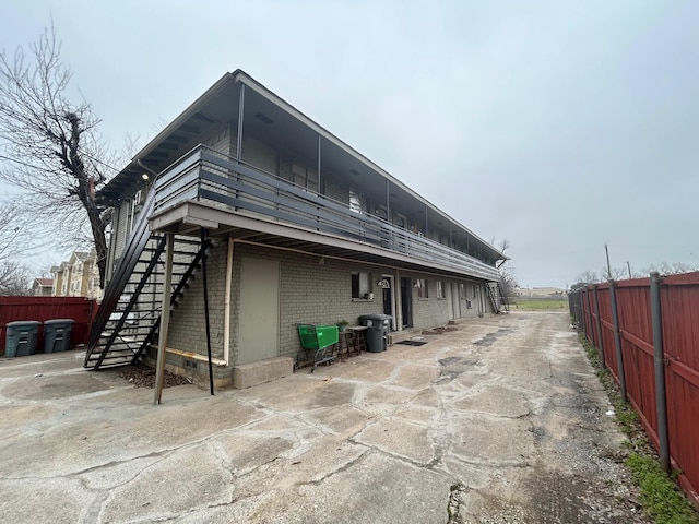 back of property with fence, stairway, and brick siding