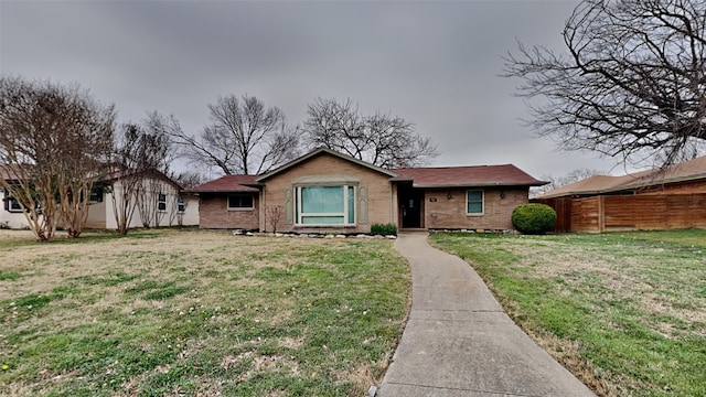 view of front of house featuring a front yard, brick siding, and fence