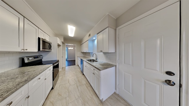 kitchen featuring light stone countertops, appliances with stainless steel finishes, white cabinets, and a sink