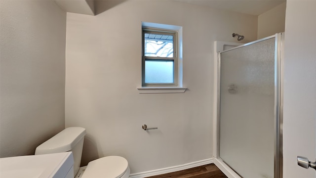 bathroom featuring toilet, a shower stall, vanity, wood finished floors, and baseboards