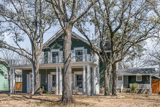 view of front of home featuring a balcony, fence, and a porch