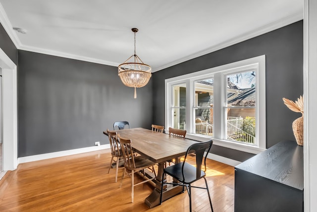 dining space with ornamental molding, baseboards, light wood finished floors, and an inviting chandelier