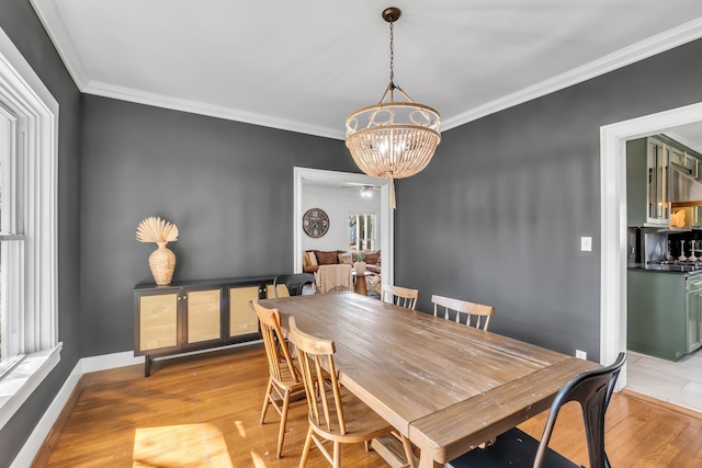 dining space with a chandelier, light wood finished floors, ornamental molding, and baseboards