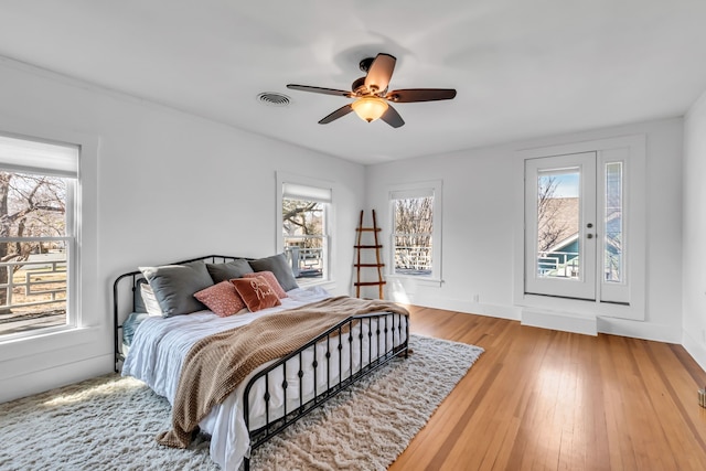 bedroom with ceiling fan, light wood-type flooring, visible vents, and baseboards