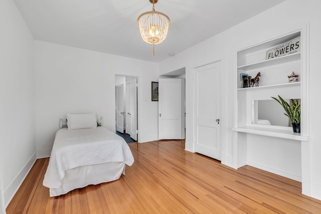 bedroom featuring baseboards, wood finished floors, and an inviting chandelier