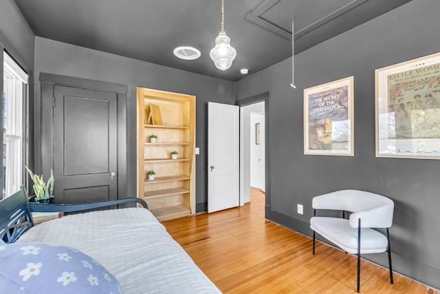 bedroom with attic access, visible vents, and light wood finished floors