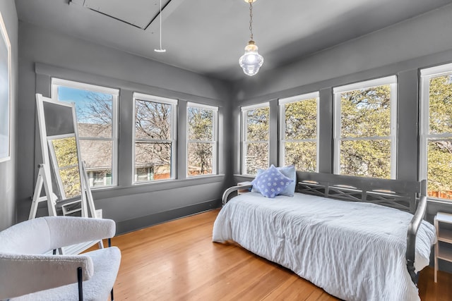 bedroom with attic access, baseboards, and wood finished floors