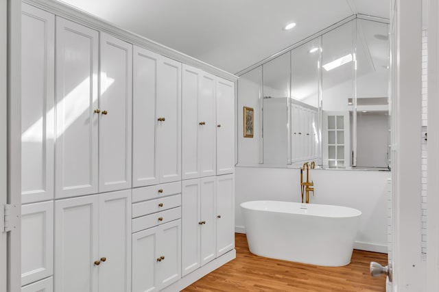 bathroom featuring recessed lighting, a soaking tub, and wood finished floors