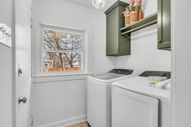 laundry area with washing machine and dryer, cabinet space, and baseboards