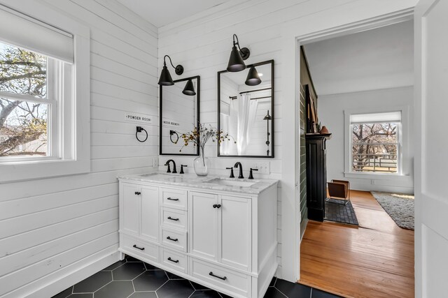 bathroom with a sink, wooden walls, and double vanity