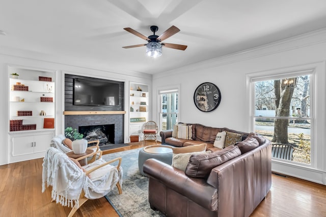 living room with wood finished floors, visible vents, built in features, ornamental molding, and a brick fireplace