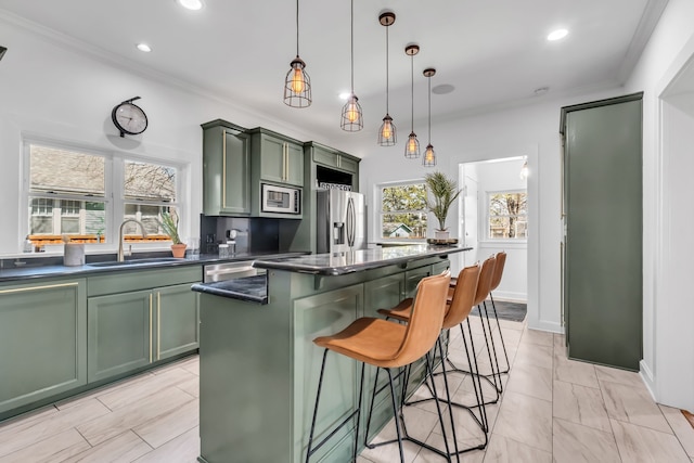 kitchen with appliances with stainless steel finishes, dark countertops, a sink, and green cabinets