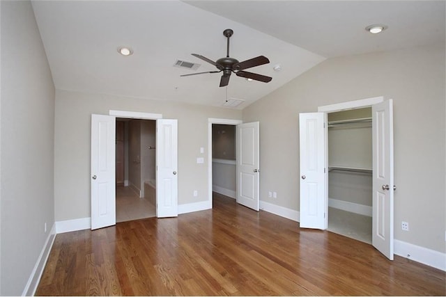 unfurnished bedroom with a closet, visible vents, vaulted ceiling, wood finished floors, and baseboards