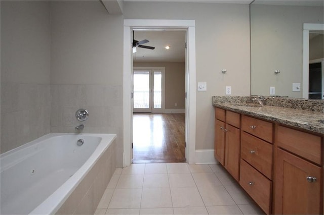 full bath with a tub to relax in, a ceiling fan, vanity, tile patterned flooring, and baseboards