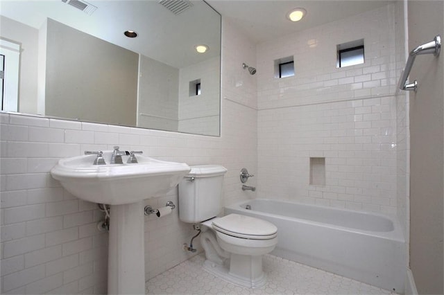 full bathroom with tile walls, shower / bathtub combination, visible vents, toilet, and tile patterned floors